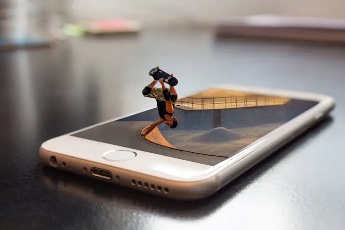 Smartphone da cui esce un ragazzo che fa una acrobazia in skateboard